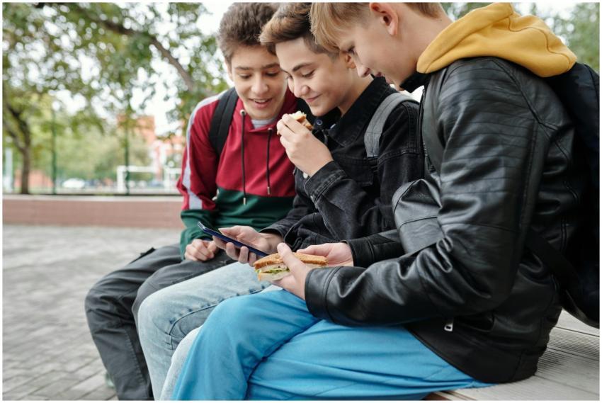 Three teenage friends sitting outdoors, enjoying s