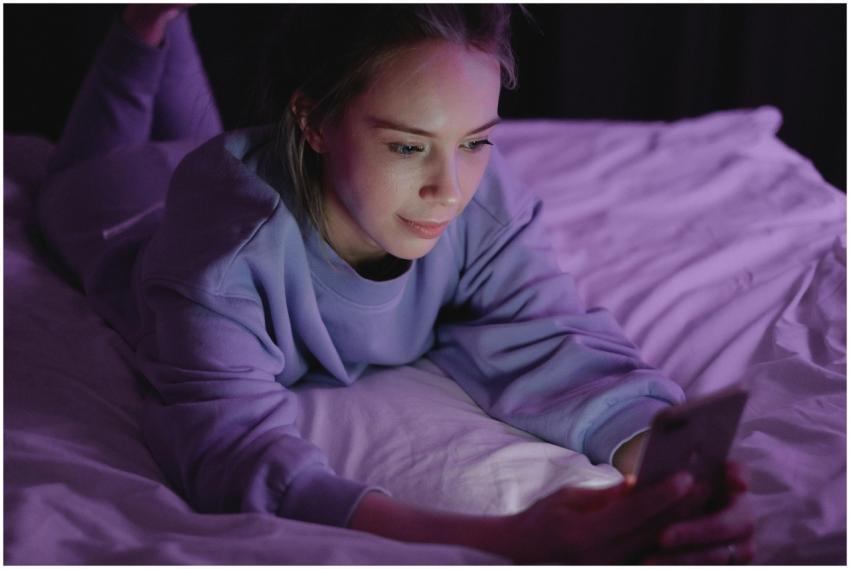A woman in pajamas looking at her smartphone while
