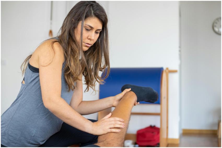 A female trainer assists a client with leg stretch