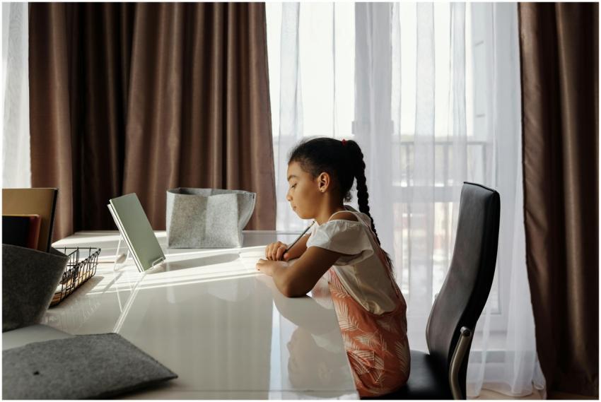 A young girl focuses intently on her homework at a