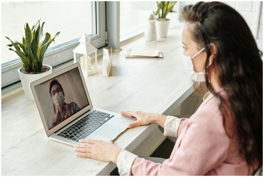 Woman and doctor video calling on laptop, both wea