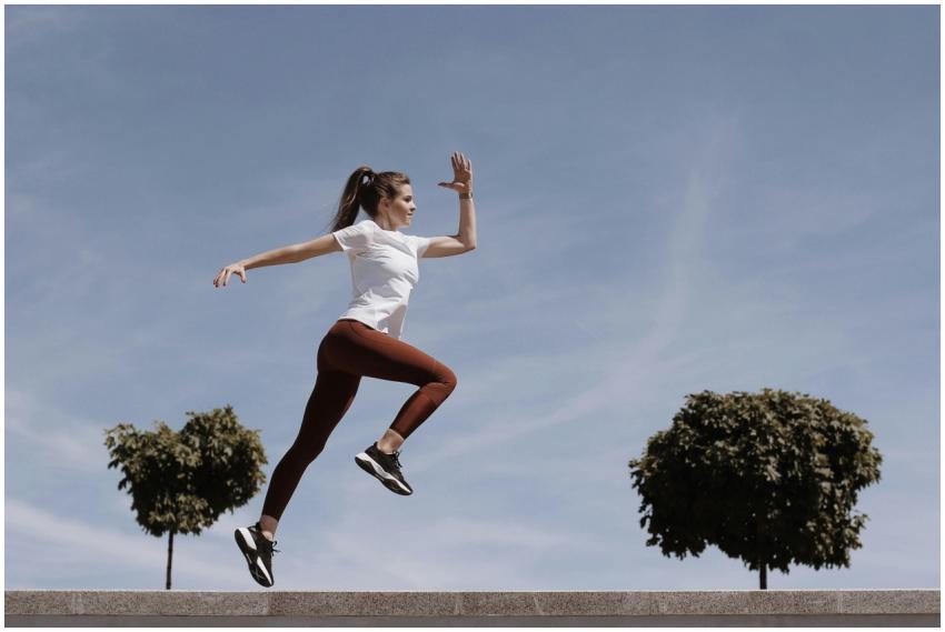 Athletic woman in action jump against a blue sky b