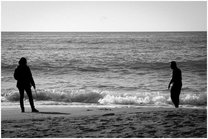 Two silhouetted figures stand on a Chilean beach,