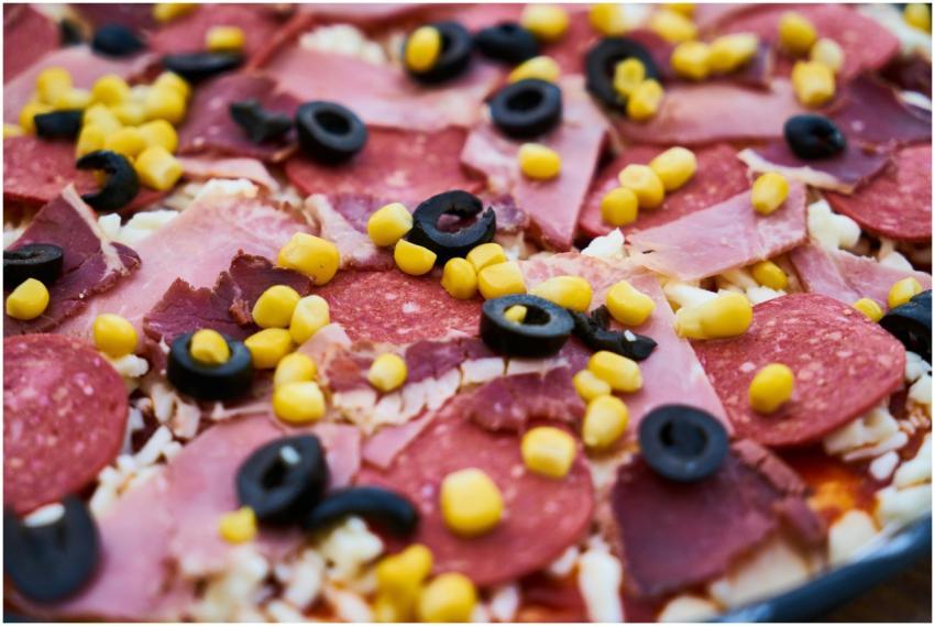 Freshly prepared meat pizza topped with olives, co