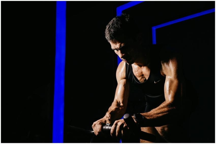 A brawny man in a black tank top intensely working