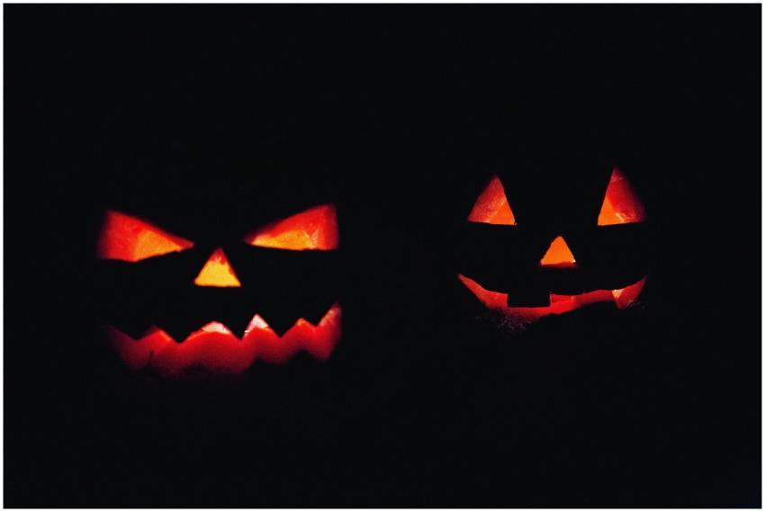 Two illuminated jack-o'-lanterns in dark, creating
