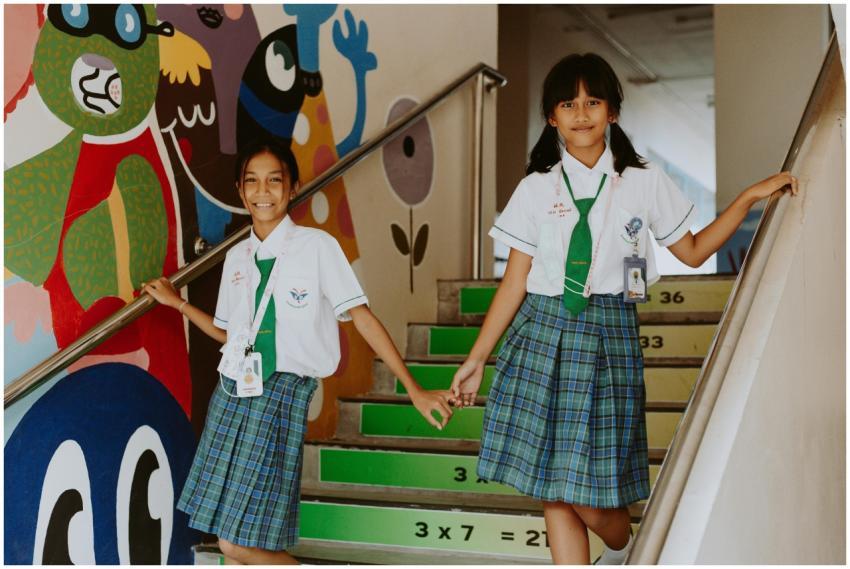 Two students in uniform smiling and walking down a