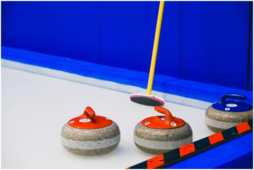 Curling stones with colorful handles and broom pla