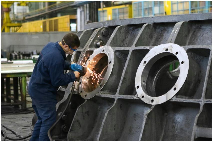 A worker in protective gear grinding metal, creati