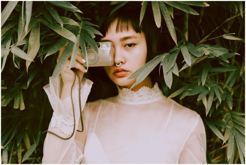 A styled portrait of a young woman hidden among lu