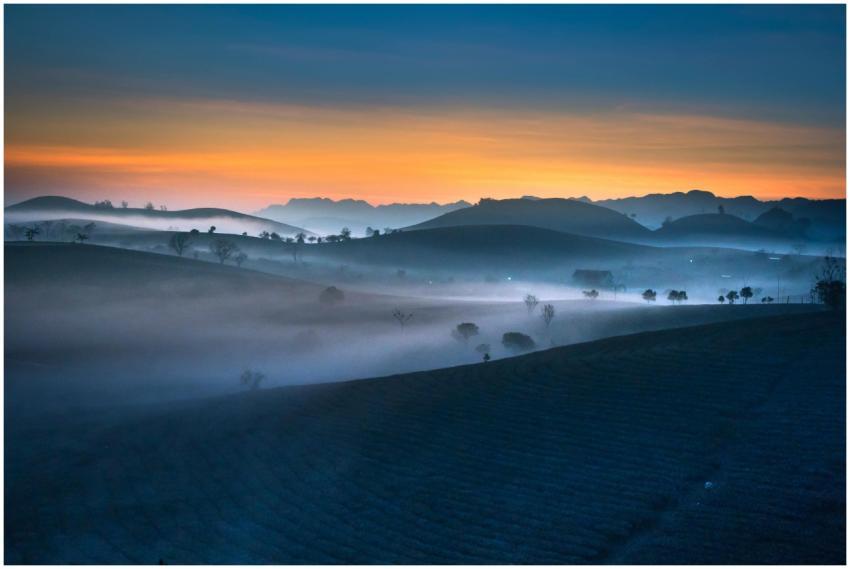 Serene landscape at dawn with fog and hills under
