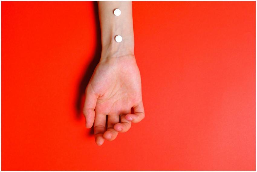 Conceptual image of pills on an arm against a bold