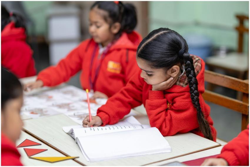 Children in red uniforms focused on writing exerci