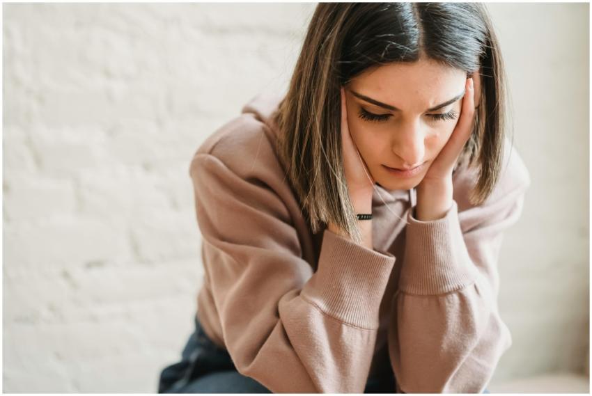 Crop unhappy female in casual wear touching cheeks