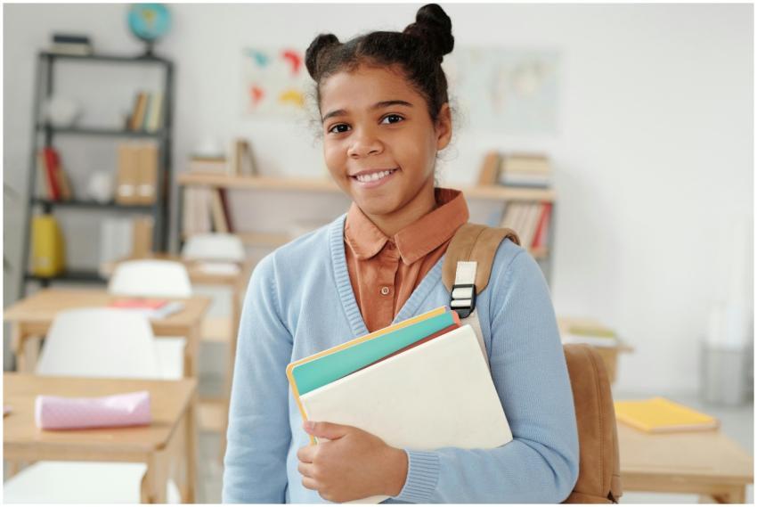 Cheerful teenager standing in classroom holding no