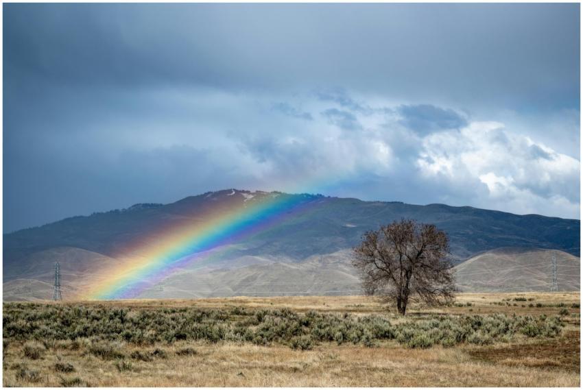 A stunning rainbow arches over a vast landscape wi