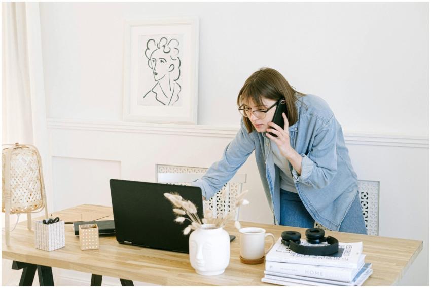 Woman multitasking with laptop and phone in modern