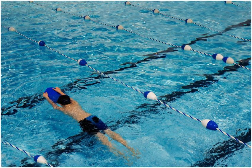 A young swimmer practicing with a kickboard in a s