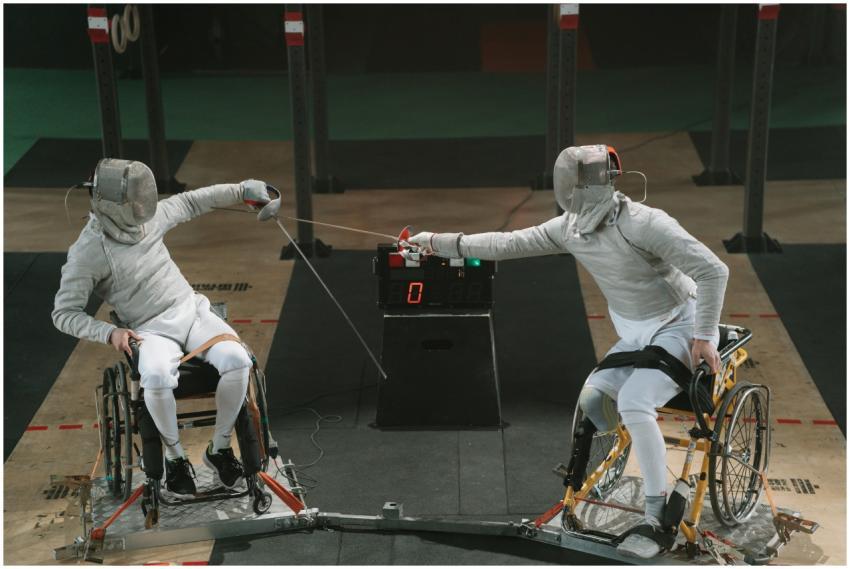 Two male wheelchair fencers in protective gear com