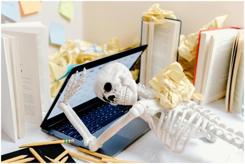 A skeleton surrounded by crumpled paper and books