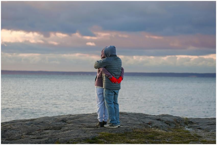 Two people hug on a rocky shore at dawn in Stamfor