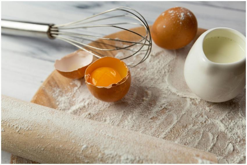 A close-up of baking essentials including eggs, fl