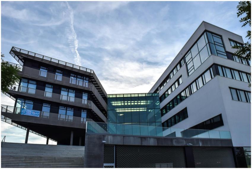 A modern glass-facade building against a blue sky,