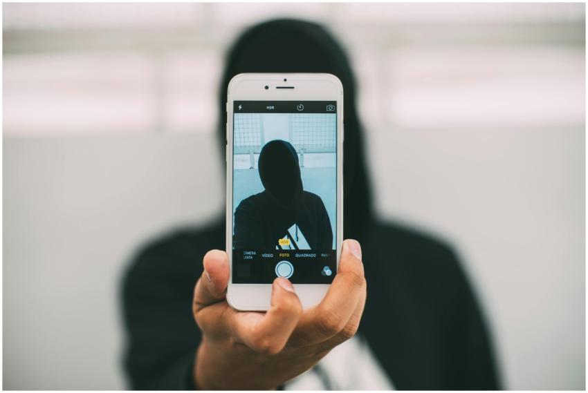 A person in a hoodie takes a mysterious selfie wit