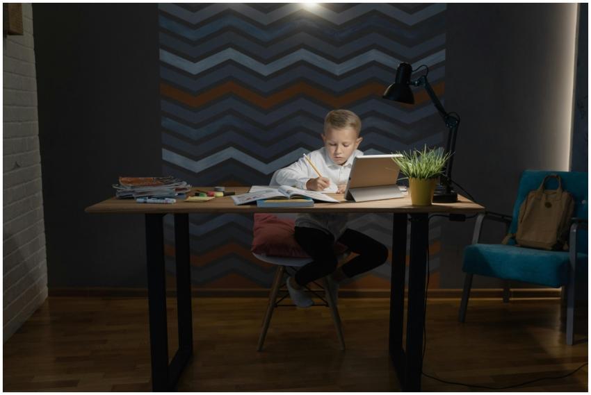 A young boy focused on his homework at a desk with