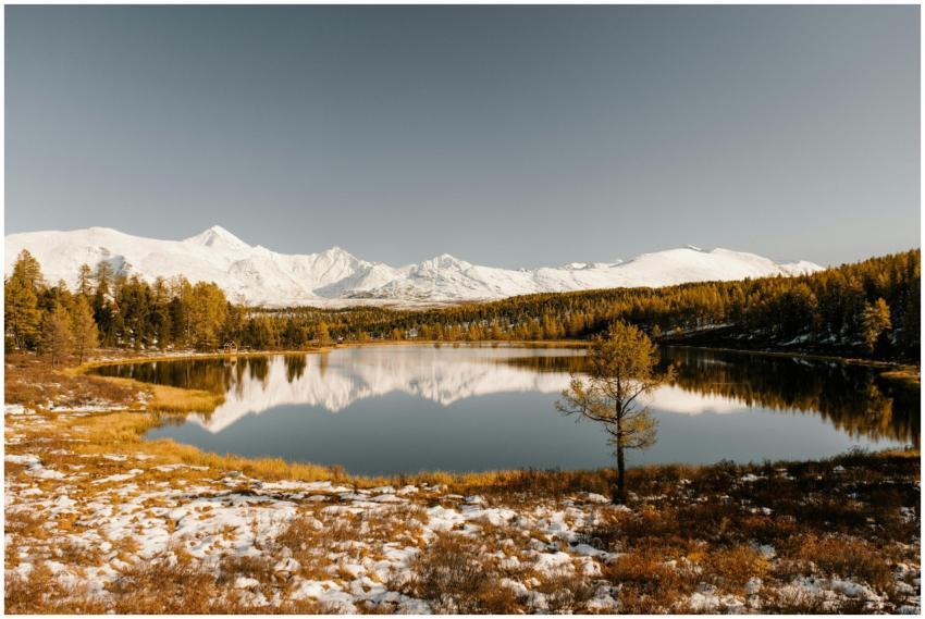 A tranquil view of a lake reflecting snow-capped m