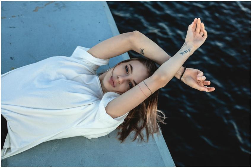 A young woman in a white t-shirt poses artisticall