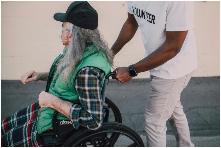 A volunteer helps a senior in a wheelchair during