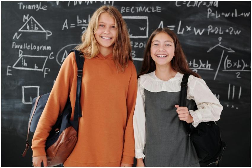 Two smiling students with backpacks standing in fr