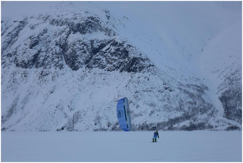 Person snowkiting against a snowy mountain backdro