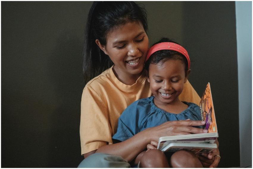 Happy mother and daughter reading a children's boo