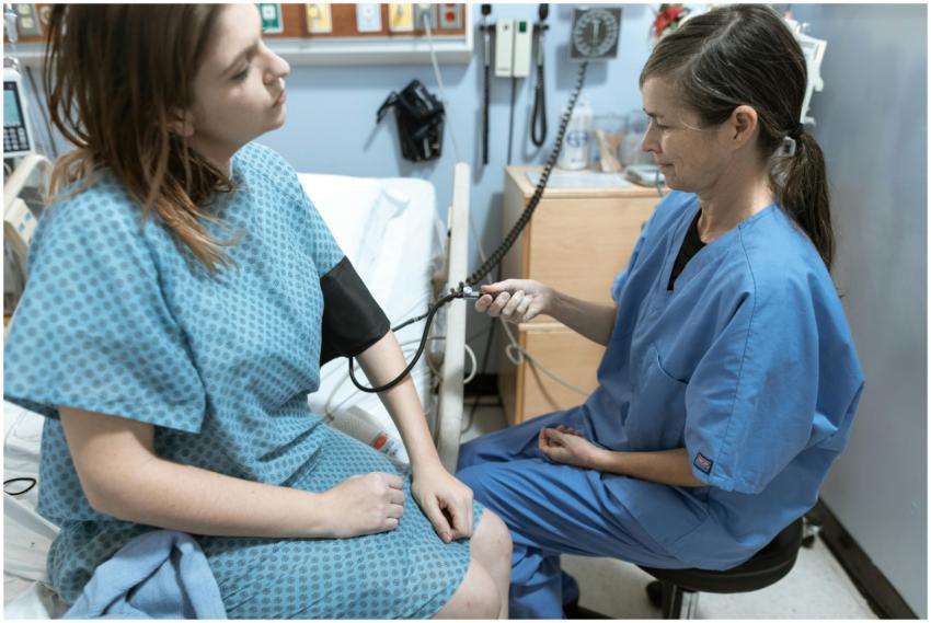 A nurse in blue scrubs checks the blood pressure o