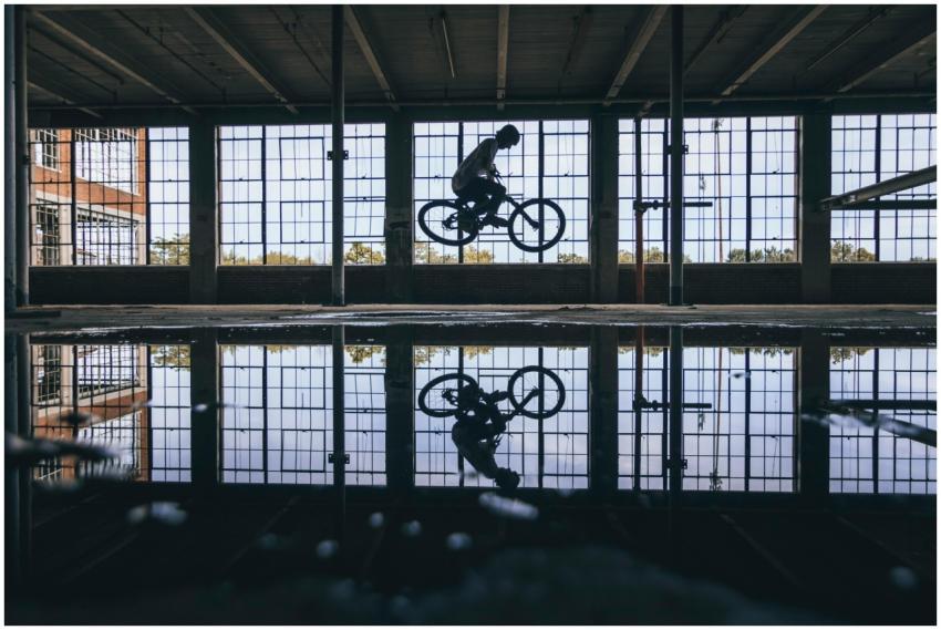 Dynamic shot of a cyclist jumping indoors, reflect
