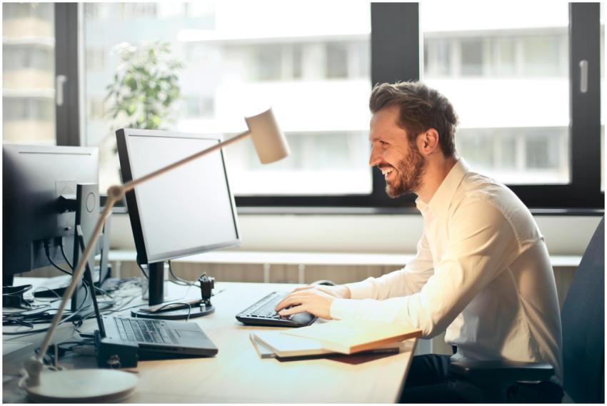 A man smiling while working at an office desk with