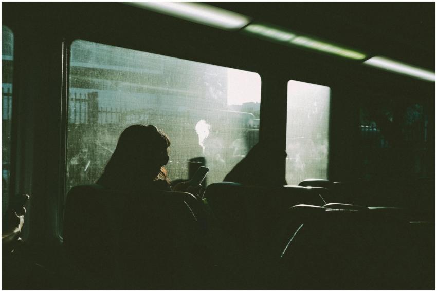 Silhouette of a person using a phone on a train jo