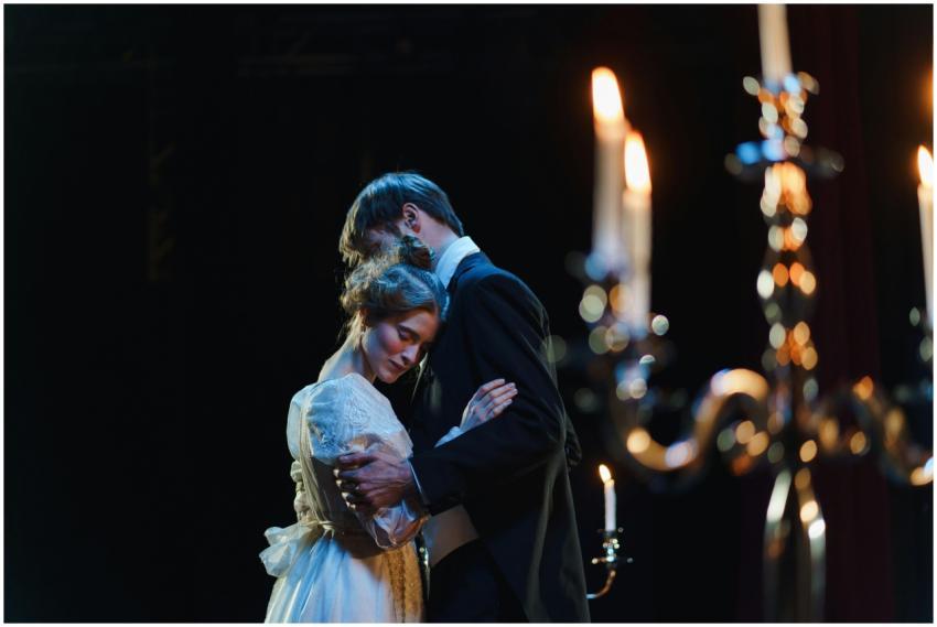 A romantic embrace on stage between actors in eleg