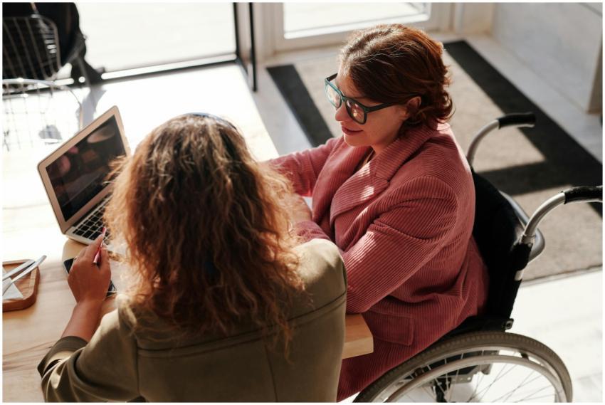 Two women working on laptops, one using a wheelcha