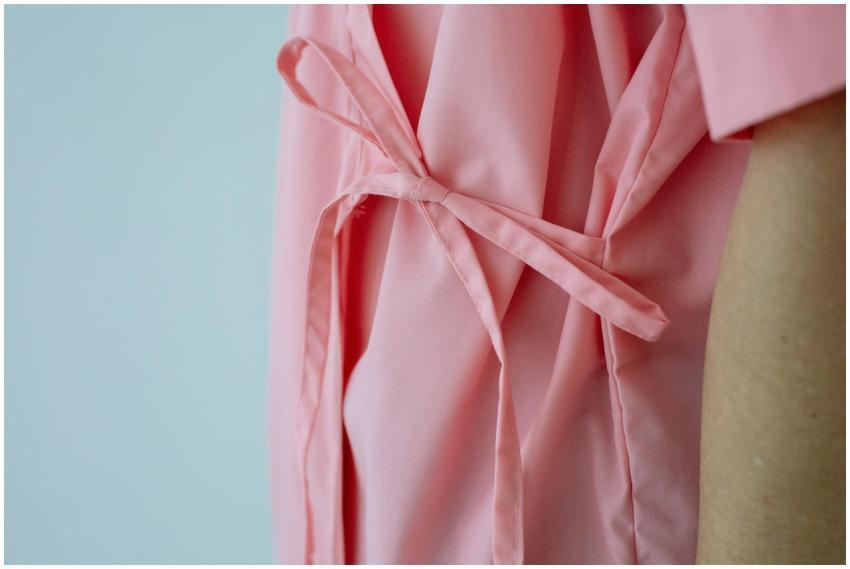 Crop unrecognizable female patient in pink gown wi