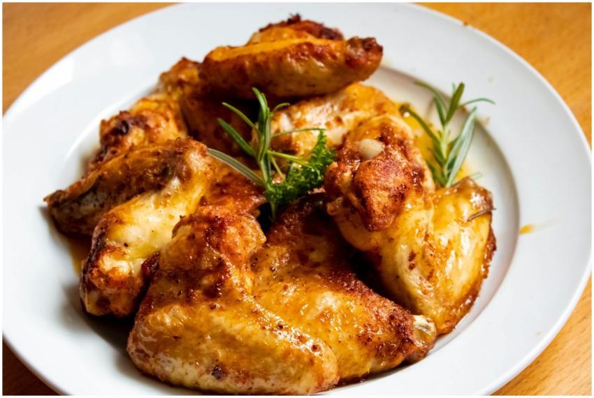 Golden-brown chicken wings garnished with fresh he
