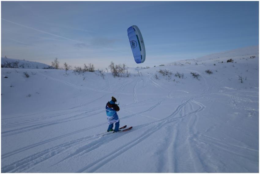 Kite skier glides across snowy landscape in Kirovs