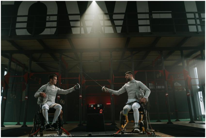 Two male wheelchair fencers in a competitive indoo