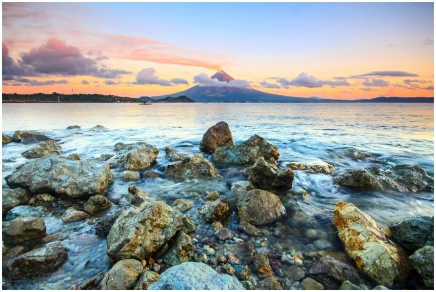 A scenic view of a sunset over a volcanic island,