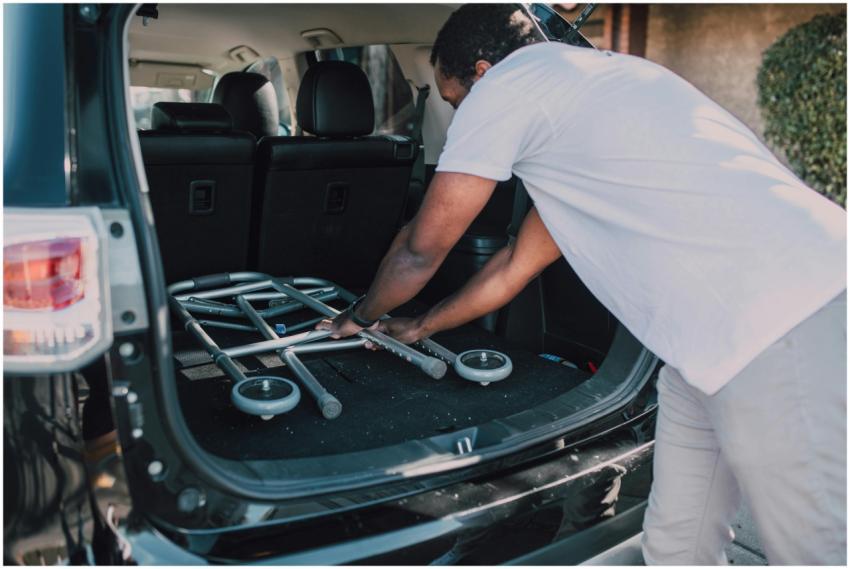 Man placing a folded walker into a car, emphasizin