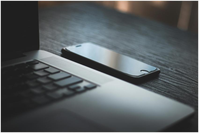 Modern laptop and smartphone on a textured wooden