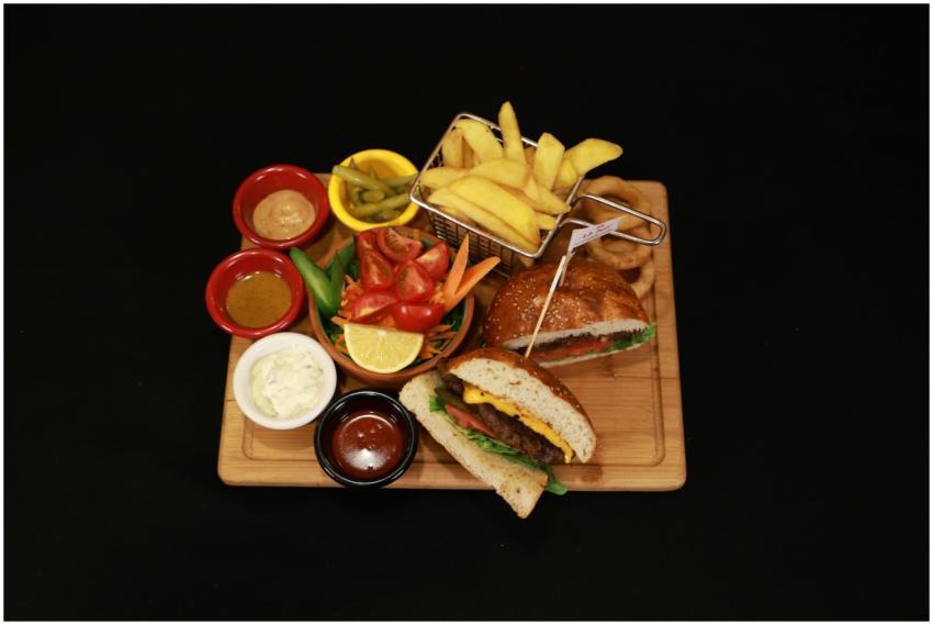 Top view of a gourmet burger meal with sides, sauc