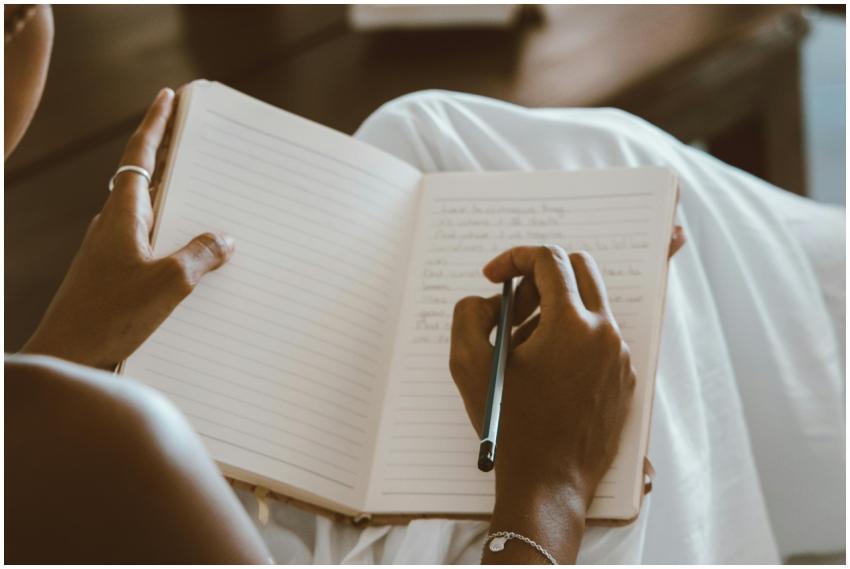 Close-up of hands writing in a journal with a penc